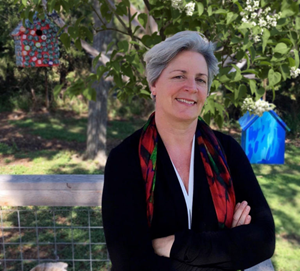 Picture of Dr Suzanne Humphries in a garden, with a birdhouse in the background